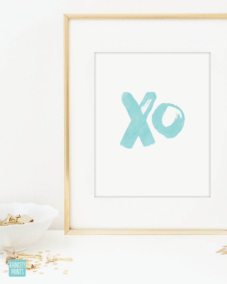 May include: A framed print with a light blue watercolor design of the letters "xo" on a white background.