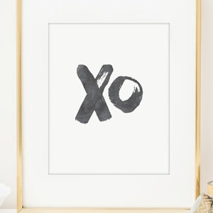 May include: A black and white print with the letters "xo" in a brushstroke style. The print is framed in a gold frame.