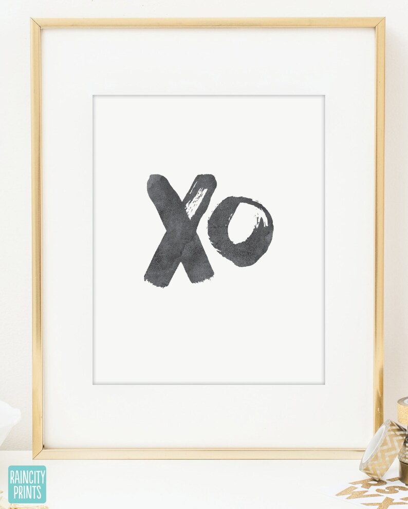 May include: A black and white print with the letters "xo" in a brushstroke style. The print is framed in a gold frame.
