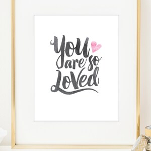 May include: A white framed print with the text "You are so Loved" in black script with a pink heart. The print is on a white background.