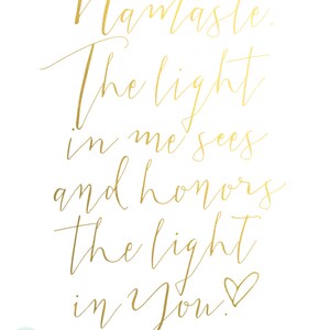 May include: A white print with gold calligraphy. The text reads "Namaste. The light in me sees and honors the light in You!" A small heart symbol follows the word "You". The words "RAINCITY PRINTS" are in the lower left corner.
