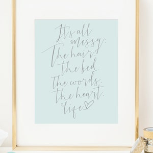 May include: A light blue printable wall art print with a gray handwritten quote that reads "It's all messy: The hair, the bed, the words, the heart, life..." with a small heart symbol at the end.