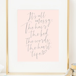 May include: A pink background with a gray cursive quote that reads "It's all messy: The hair. The bed. The words. The heart. Life..." with a small heart symbol at the end.