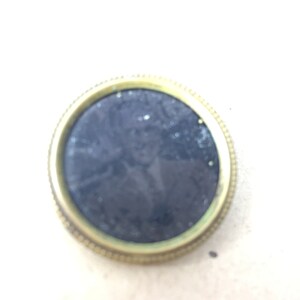 May include: A gold-colored round locket with a black and white photo of a person inside.