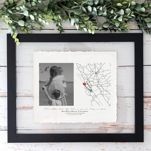 May include: Black framed print with a black and white photo and a map. The photo shows a family. The map has a red heart marking a location. Text at the bottom reads "Red Rock Beach, California".