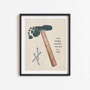 May include: A framed print with a green footprint shaped like a hammer and three silver nails. The print has the text "I love building memories with you, love, Shelly".