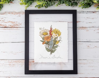 May include: A framed print with a floral bouquet of yellow, orange, white, and blue flowers. The print has the text "Nana's Garden" and a list of names below it.