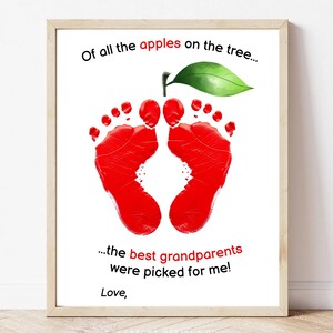 May include: Framed print in a light wood frame. The artwork shows a red apple shape formed by footprints, with a green leaf and stem. Text reads, "Of all the apples on the tree... the best grandparents were picked for me!"