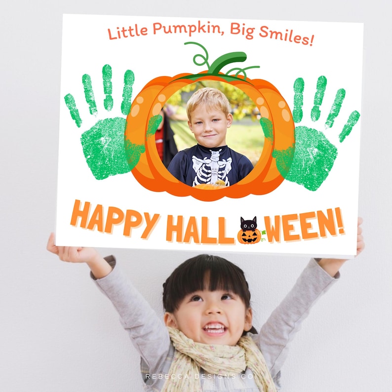 May include: A white rectangular sign featuring the text Little Pumpkin, Big Smiles! at the top and HAPPY HALL-WEEN! at the bottom. The centre displays an orange pumpkin frame containing a photo of a child, flanked by two green handprints.
