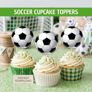 Op de afbeelding: Drie cupcakes met ronde voetbaldecoraties als toppers. Elke cupcake is voorzien van witte glazuur en staat in een groen-wit geblokt papieren vormpje. De voetbaltoppers zijn zwart-wit met een klassiek zeshoekig patroon.