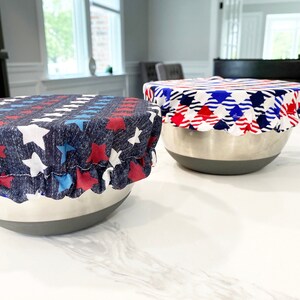 May include: Two reusable bowl covers in red, white, and blue star patterns. The covers are made of fabric and are designed to fit over bowls to keep food fresh.