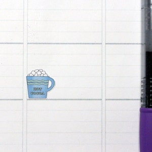 May include: A blue and white mug with a white rim and a white handle. The mug is filled with white marshmallows and has the text "HOT COCOA" printed on the front.