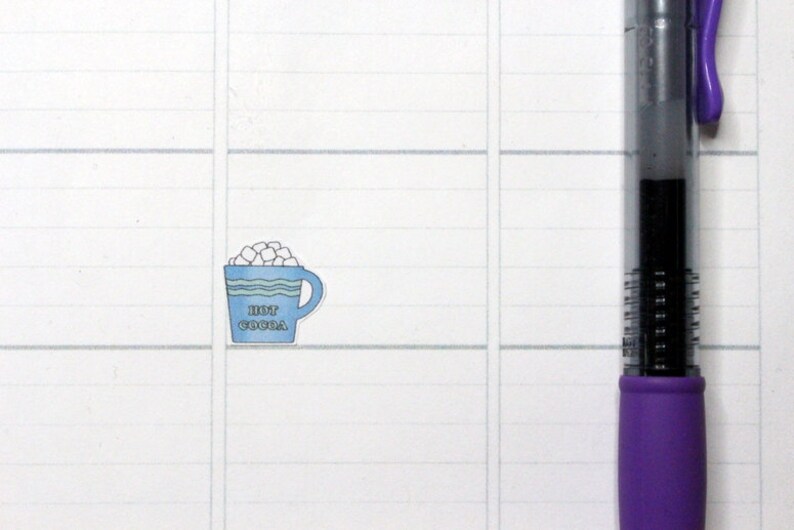 May include: A blue and white mug with a white rim and a white handle. The mug is filled with white marshmallows and has the text "HOT COCOA" printed on the front.