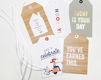 May include: Five gift tags with different designs and sayings. The tags are made of wood and paper and have a hole at the top for string. The sayings on the tags are: "You are my home and adventure all at once", "Hooray!", "Today is your day", "Let's celebrate", and "You've earned this."