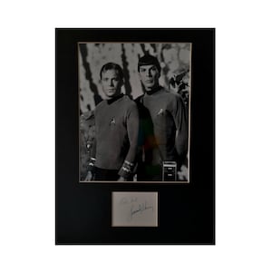 May include: Black and white photo of two men in Star Trek uniforms, signed by William Shatner and Leonard Nimoy. The photo is framed in black.