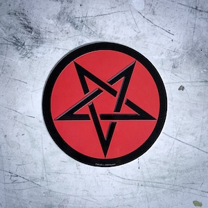 May include: A red circle sticker with a black pentagram inside. The pentagram is a five-pointed star with each point extending to the edge of the circle.