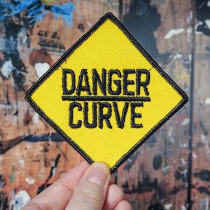 May include: Yellow diamond-shaped patch with black embroidered text that reads "DANGER CURVE".