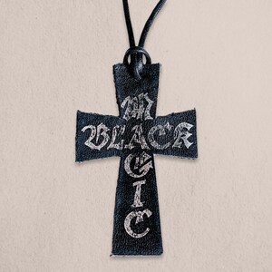 以下が含まれることがあります： 「My Black Circle」と銀色の文字が刻まれた、黒い革製の十字架のペンダントネックレスです。