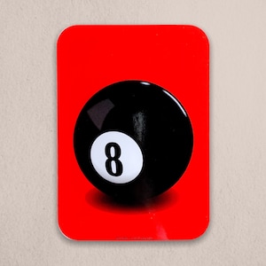 May include: A black and white 8-ball with a red background. The 8-ball is a classic pool ball with a white number 8 on it.