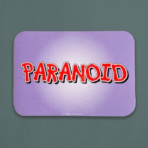 May include: A purple coaster with the word "PARANOID" written in red, bold letters. The letters have a 3D effect and are outlined in black.