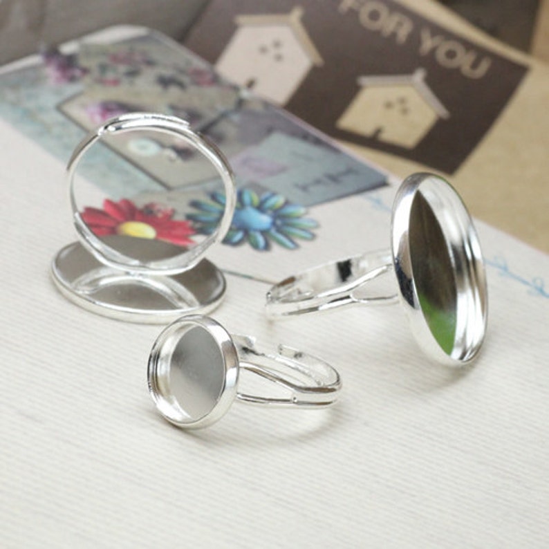 May include: Three silver rings with round, clear glass cabochons. The rings are adjustable and have a simple design.