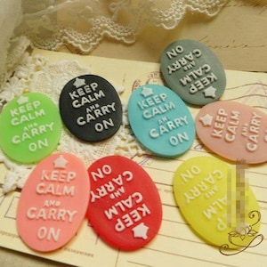 Può includere: Sette bottoni ovali e colorati in resina con il testo "Keep Calm and Carry On" in lettere bianche. I bottoni sono decorati con una stella.