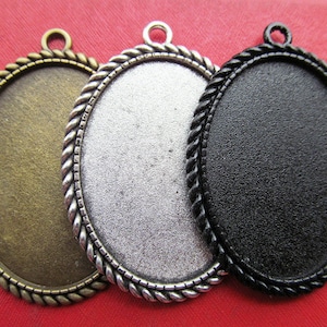 Może przedstawiać: Trzy owalne metalowe ramki do zdjęć z ozdobnym sznurkowym obramowaniem. Ramki są srebrne, złote i czarne.