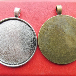 Puede incluir: Dos blancos redondos de metal para la elaboración de joyas. Uno es plateado y el otro es bronce.