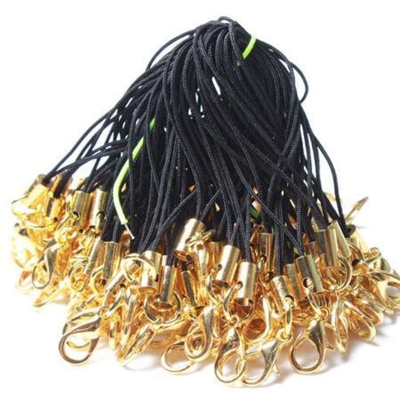 May include: A bulk pack of black string with gold lobster claw clasps. The string is approximately 18 inches long and is ideal for making keychains, phone charms, or other small crafts.