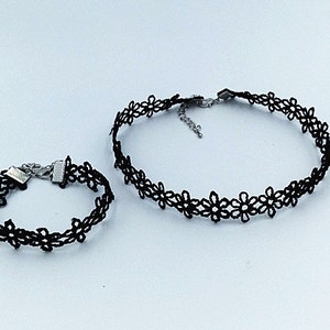 Può includere: Un set di due collane di pizzo nero con delicati motivi floreali. La collana più grande è una collana, mentre la collana più piccola è un braccialetto.
