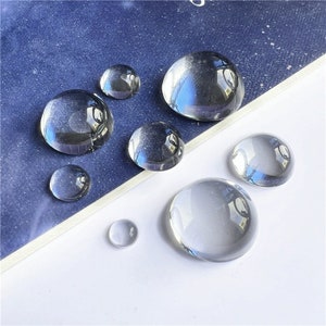 May include: Assortment of clear glass cabochons in various sizes. The cabochons are round and have a smooth, polished surface.