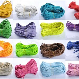 Könnte beinhalten: Sortiment von 16 Spulen geflochtener Schnur in verschiedenen Farben, darunter Gelb, Weiß, Blau, Grün, Lila, Orange, Limettengrün, Braun, Beige, Rosa, Hellblau und Rosa. Die Schnur besteht aus einem gewebten Material und eignet sich für Bastelarbeiten.