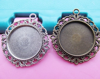 May include: Two silver and bronze pendant trays with ornate filigree designs. The trays are round and have a smooth, shiny surface. They are perfect for adding a touch of elegance to your jewelry making projects.