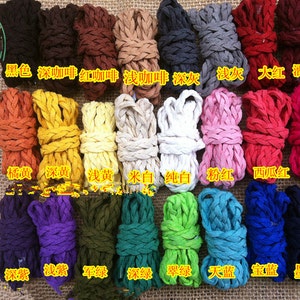 Peut inclure: Une collection de 20 cordons tressés de différentes couleurs, notamment noir, marron, rouge, orange, jaune, blanc, rose, vert, bleu et violet. Les cordons sont disposés en rangées sur un fond en toile de jute. Le texte sous chaque cordon identifie la couleur en chinois.