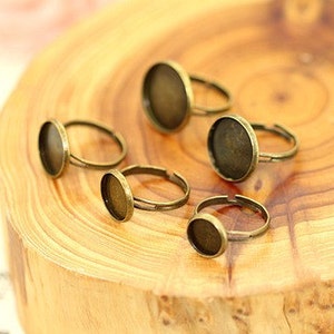May include: Five bronze-coloured rings with round glass inserts. The rings are on a wooden surface.