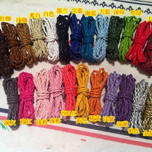 Può includere: Assortimento di cordoni in pelle intrecciati in vari colori, tra cui rosso, bianco, nero, blu, verde, argento, oro e marrone. I cordoni sono disposti in file ed etichettati con i loro colori corrispondenti in caratteri cinesi.