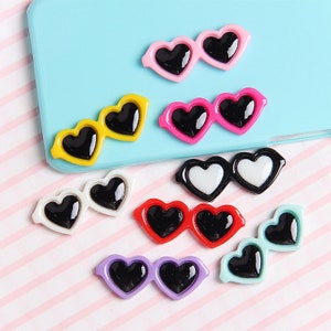 May include: Assortment of colorful heart-shaped sunglasses with black lenses. The sunglasses are made of plastic and have a shiny finish.