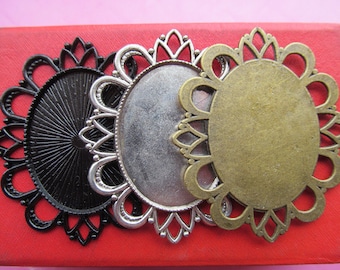 May include: Three metal oval-shaped picture frames with decorative filigree edges. The frames are black, silver, and gold.