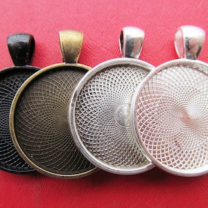 Puede incluir: Cuatro bandejas redondas de metal para colgantes con un patrón de rejilla decorativo. Las bandejas son de color negro, bronce, plata y blanco.