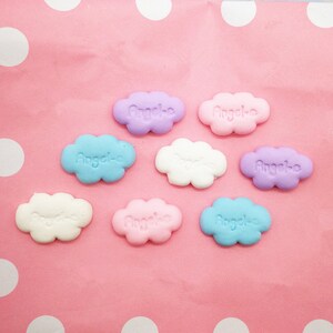 Peut inclure: Sept breloques en forme de nuage de couleur pastel avec le mot "Angele" écrit sur chacune d'elles.