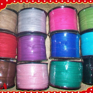 May include: A collection of spools of colorful cord in various shades, including brown, silver, pink, green, red, purple, blue, and teal. Each spool is wrapped in clear plastic, showcasing the cord's texture and color. The cords are neatly arranged.