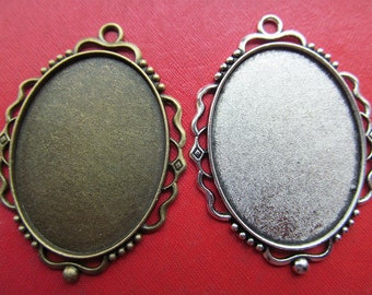 Puede incluir: Dos marcos de fotos ovalados de metal con bordes ornamentados. Un marco es plateado y el otro es bronce.