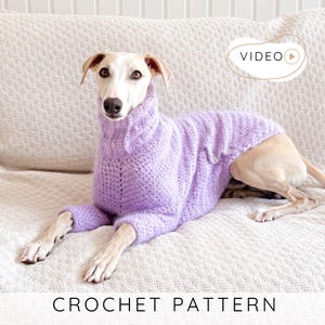 May include: A light purple crochet dog sweater with a turtleneck collar. The dog is lying on a white textured surface. The text "CROCHET PATTERN" is at the bottom of the image.