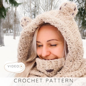 Könnte beinhalten: Eine beige Häkelbärenhaube mit angenähten Ohren und einem Halstuch. Die Kapuze ist aus einem strukturierten Garn gefertigt und hat ein braunes Nasendetail. Das Bild hat unten den Text "CROCHET PATTERN".