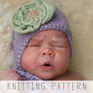 newborn in violet earflap hat with big knitted flower