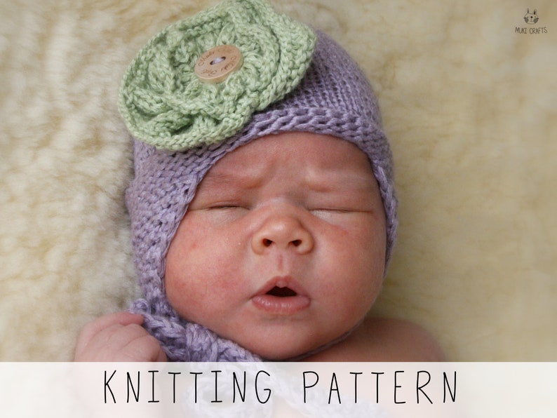 newborn in violet earflap hat with big knitted flower