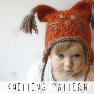 girl wearing orange ear flap hat with tassels and embroidery nose with whiskers, knitting pattern to make kids winter hat