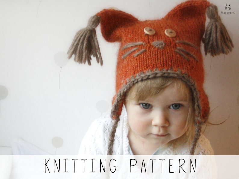 girl wearing orange ear flap hat with tassels and embroidery nose with whiskers, knitting pattern to make kids winter hat