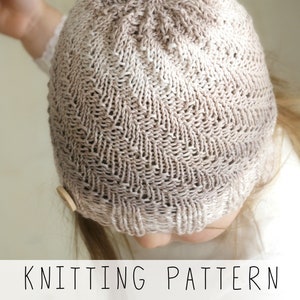 toddler in light hand knitted hat with a spiral texture, knitting pattern to make kids hat