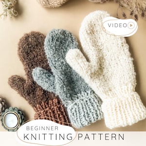 Op de afbeelding: Drie gebreide wanten in bruin, grijs en crème, elk met een getextureerde, pluizige garenstructuur en een geribbelde boord. De afbeelding bevat de tekst "VIDEO" in de rechterbovenhoek en "BEGINNER KNITTING PATTERN" aan de onderkant.